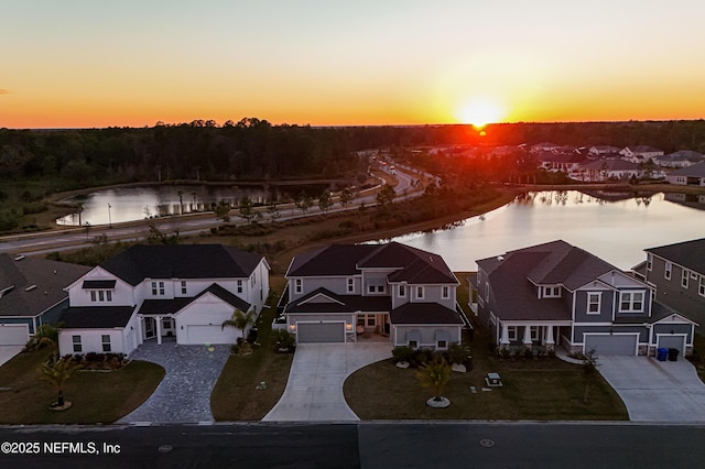 aerial view at dusk featuring a water view and a residential view