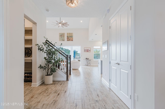 corridor featuring stairway, light wood-style flooring, and baseboards