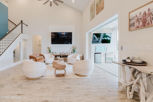 living room featuring stairs, high vaulted ceiling, wood finished floors, and a ceiling fan