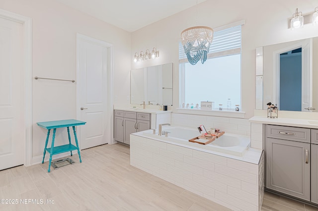 bathroom featuring a garden tub, plenty of natural light, and two vanities