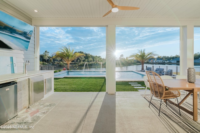 sunroom featuring wood ceiling, plenty of natural light, a ceiling fan, and a water view