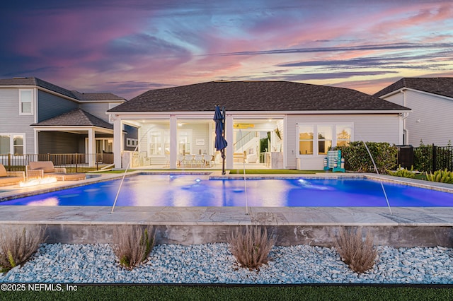 pool at dusk with fence and a patio