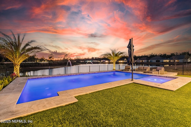 pool at dusk with a fenced in pool, a lawn, a fenced backyard, an in ground hot tub, and a patio area