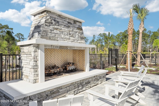 view of patio featuring an outdoor stone fireplace and fence