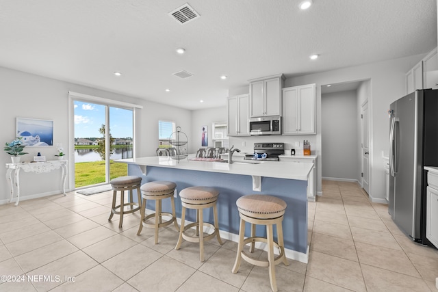 kitchen with appliances with stainless steel finishes, a center island with sink, sink, and light tile patterned floors