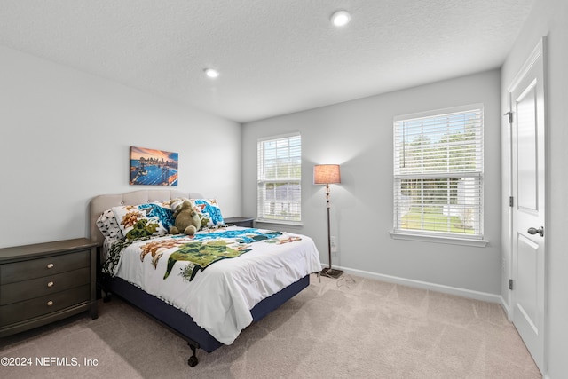 carpeted bedroom featuring a textured ceiling and multiple windows