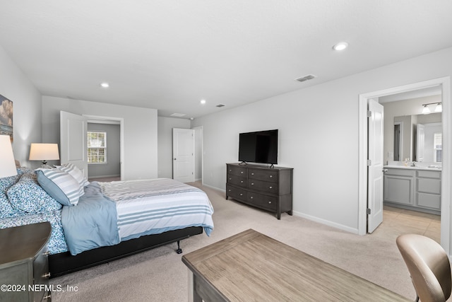 bedroom with light colored carpet and ensuite bathroom