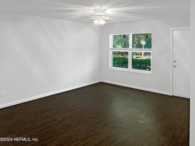 spare room featuring dark wood-type flooring and ceiling fan