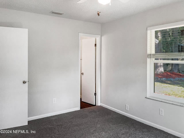 carpeted empty room with ceiling fan, a textured ceiling, and a healthy amount of sunlight