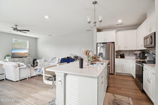 kitchen with light wood-type flooring, sink, white cabinetry, a center island with sink, and appliances with stainless steel finishes