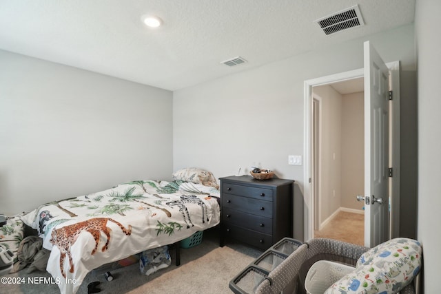 bedroom with a textured ceiling and light colored carpet