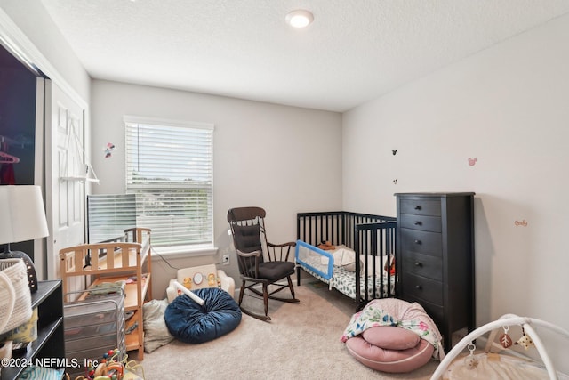 carpeted bedroom featuring a textured ceiling and a crib