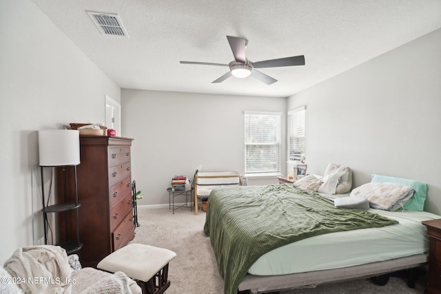 bedroom with ceiling fan, light colored carpet, and a textured ceiling