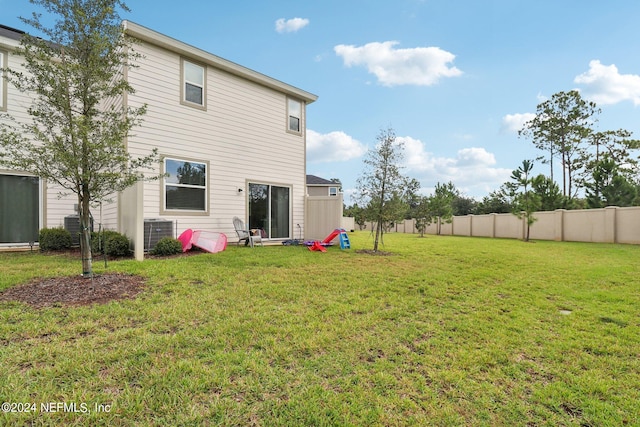 back of house featuring central AC and a yard