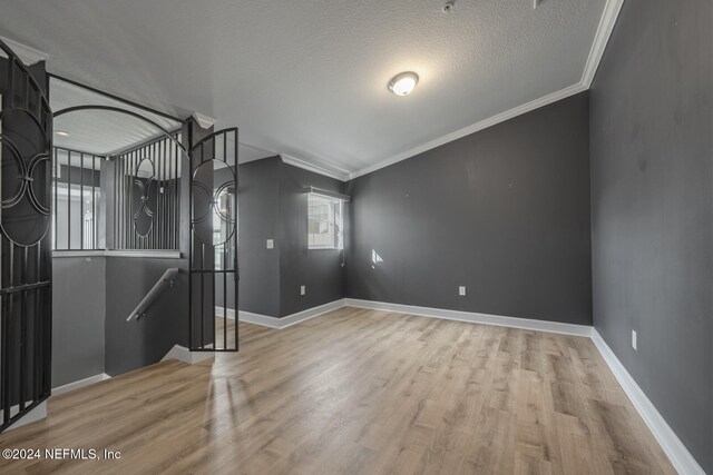 unfurnished room featuring light hardwood / wood-style floors, ornamental molding, and a textured ceiling