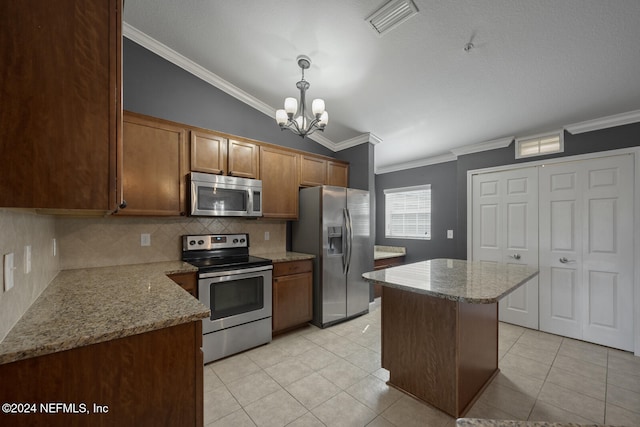 kitchen with lofted ceiling, crown molding, appliances with stainless steel finishes, decorative light fixtures, and a kitchen island