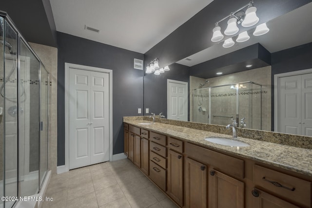 bathroom featuring vanity, tile patterned floors, a shower with shower door, and a notable chandelier