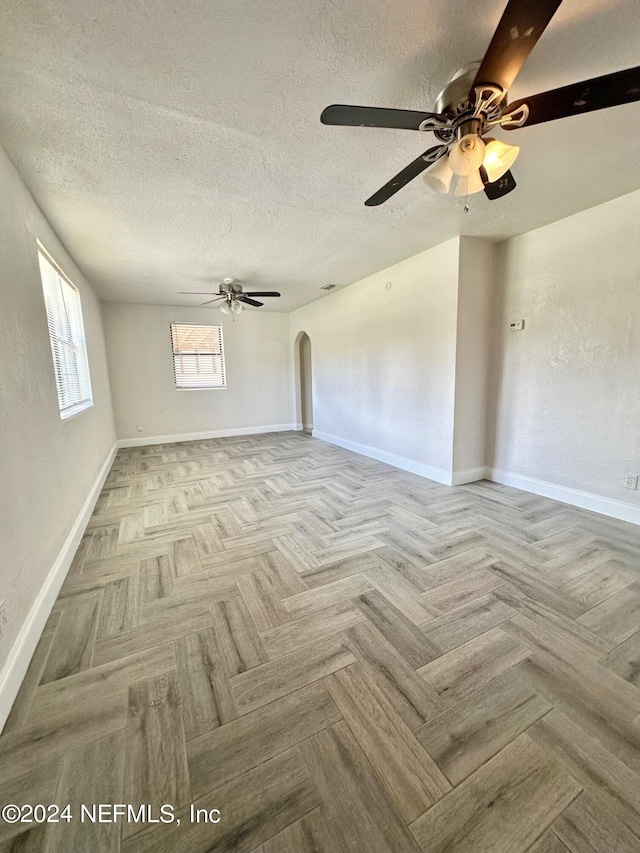 unfurnished living room with light parquet floors, a textured ceiling, and ceiling fan