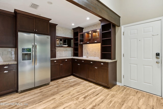 kitchen with stainless steel fridge, light stone countertops, dark brown cabinetry, and light hardwood / wood-style flooring