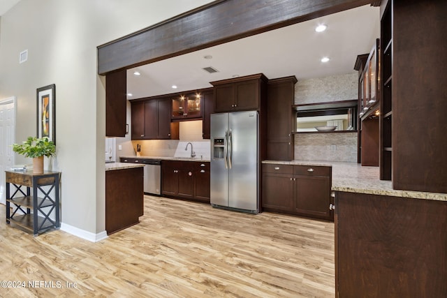 kitchen featuring dark brown cabinetry, light stone countertops, stainless steel appliances, and light wood-type flooring