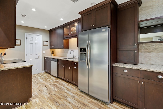 kitchen with light wood-type flooring, light stone countertops, sink, appliances with stainless steel finishes, and dark brown cabinets