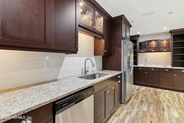 kitchen featuring light wood-type flooring, sink, light stone countertops, backsplash, and appliances with stainless steel finishes