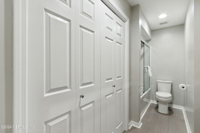 bathroom with shower / bath combination with glass door and toilet