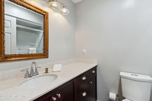 bathroom with vanity, a shower with door, and toilet