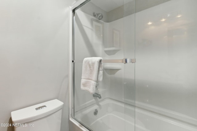 bathroom with combined bath / shower with glass door and toilet