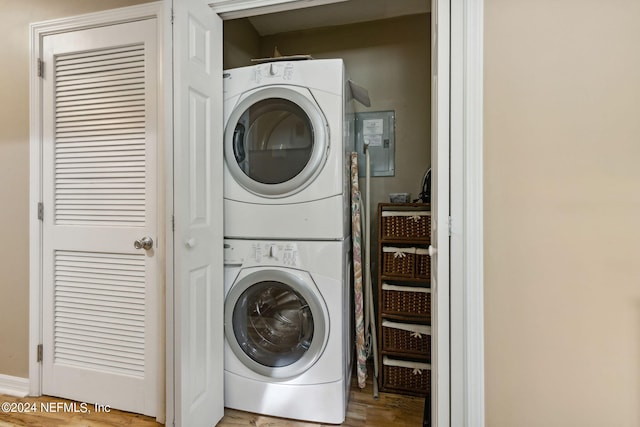 washroom with electric panel, light hardwood / wood-style floors, and stacked washer / drying machine