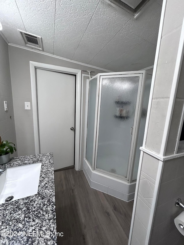 bathroom featuring wood-type flooring, a textured ceiling, vanity, and a shower with door