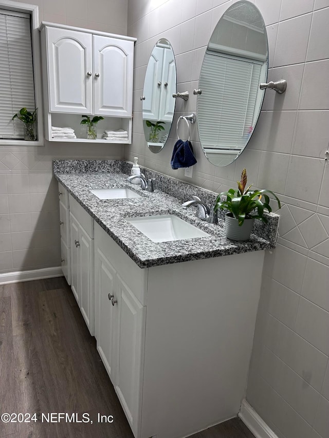 bathroom featuring wood-type flooring, vanity, and tile walls