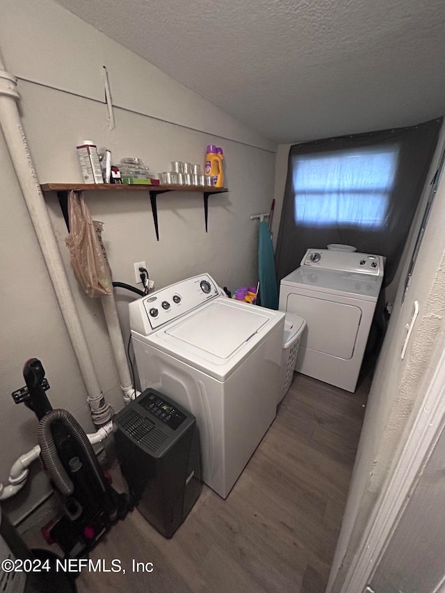 clothes washing area with a textured ceiling, hardwood / wood-style flooring, and washing machine and dryer