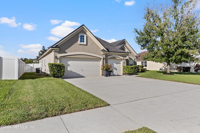 view of front of house with cooling unit, a garage, and a front lawn