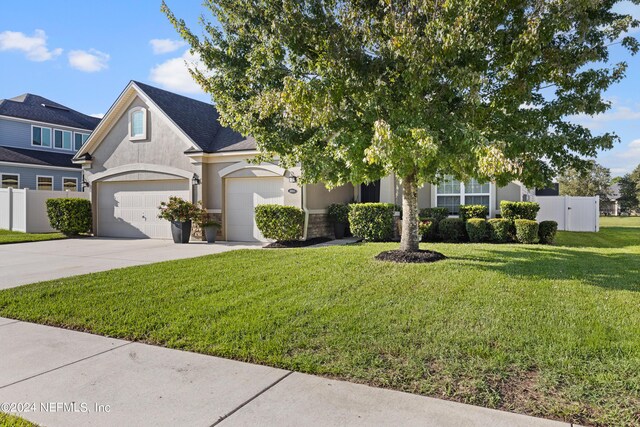 view of property hidden behind natural elements with a garage and a front lawn