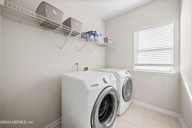 clothes washing area with light tile patterned flooring, a healthy amount of sunlight, and washing machine and dryer