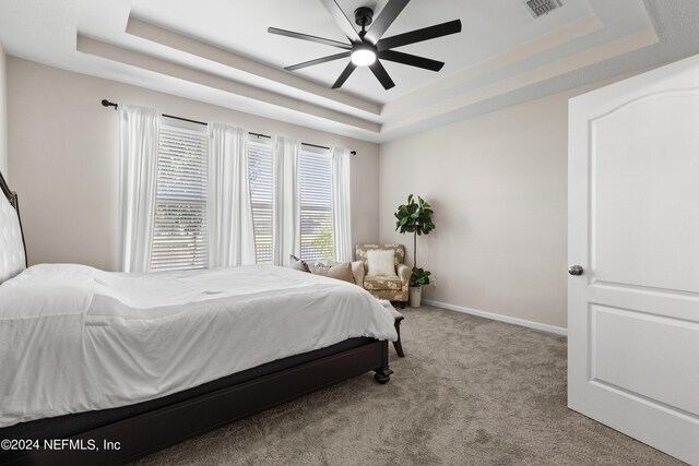 carpeted bedroom featuring a tray ceiling and ceiling fan