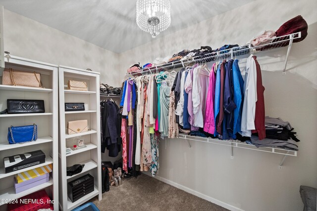 walk in closet featuring carpet floors and a notable chandelier