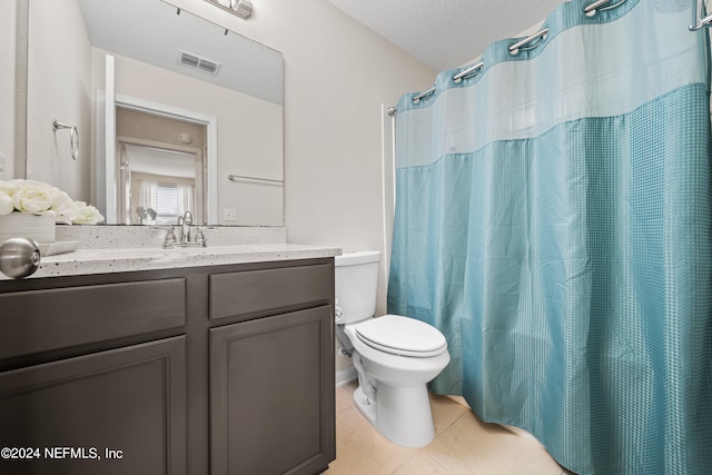 bathroom with a textured ceiling, a shower with shower curtain, tile patterned floors, vanity, and toilet