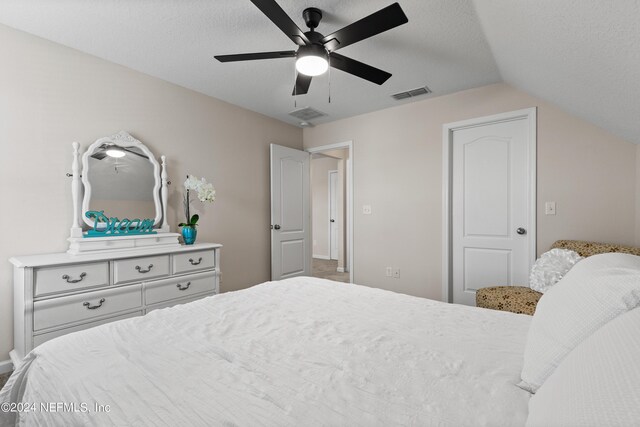 bedroom featuring vaulted ceiling, ceiling fan, and a textured ceiling