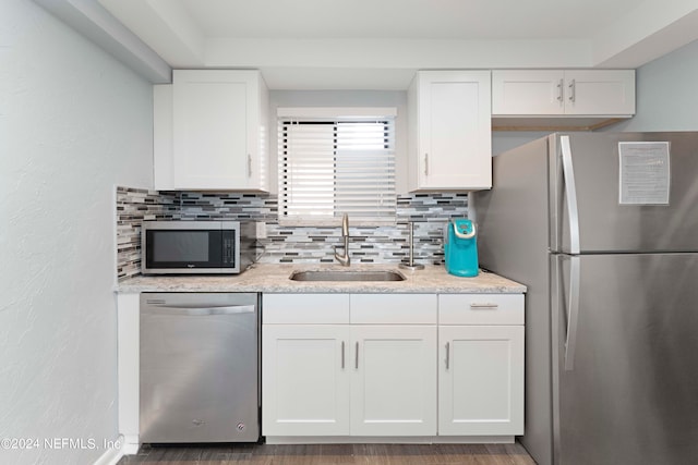 kitchen with appliances with stainless steel finishes, sink, tasteful backsplash, and white cabinetry