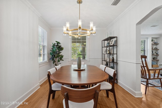 dining space featuring a notable chandelier, light hardwood / wood-style flooring, and crown molding