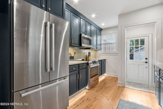 kitchen featuring light hardwood / wood-style flooring, stainless steel appliances, blue cabinets, and decorative backsplash