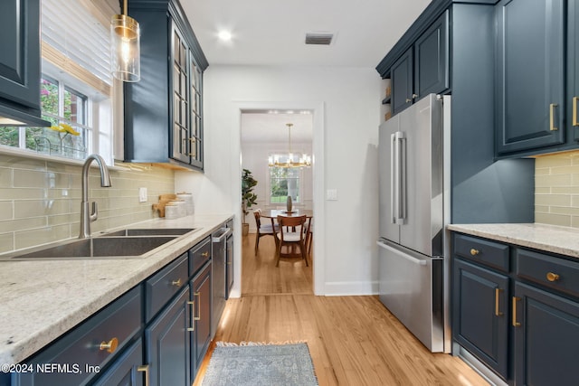 kitchen with sink, a notable chandelier, light hardwood / wood-style flooring, stainless steel appliances, and decorative light fixtures