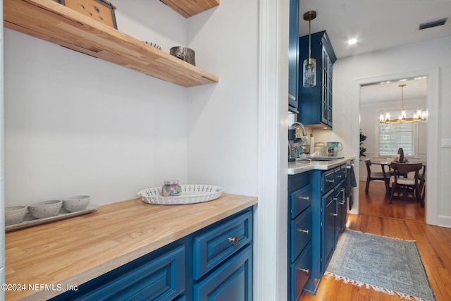 kitchen with sink, decorative light fixtures, blue cabinetry, dark hardwood / wood-style floors, and a notable chandelier