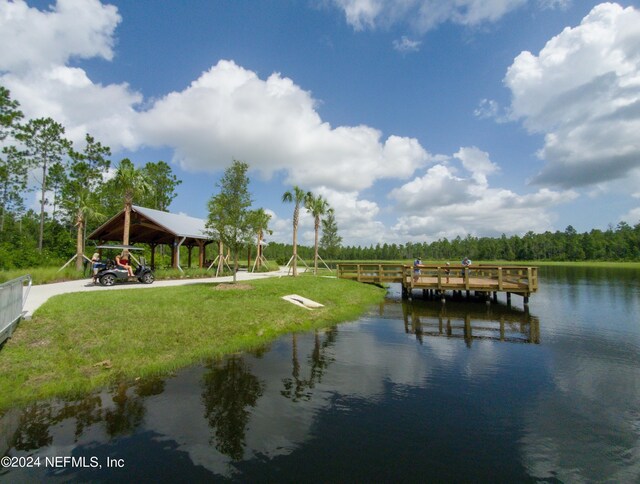 dock area with a gazebo, a water view, and a lawn