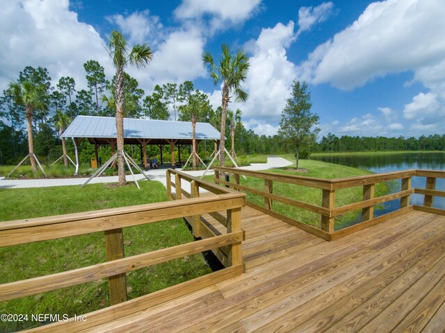 wooden deck featuring a water view and a lawn