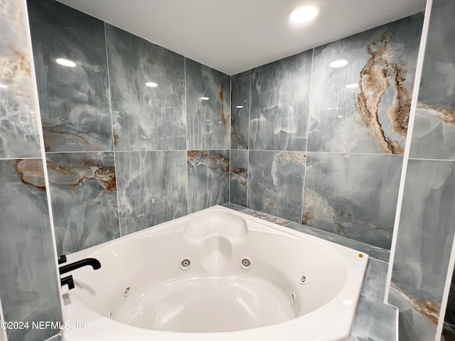 bathroom featuring tiled tub and tile walls