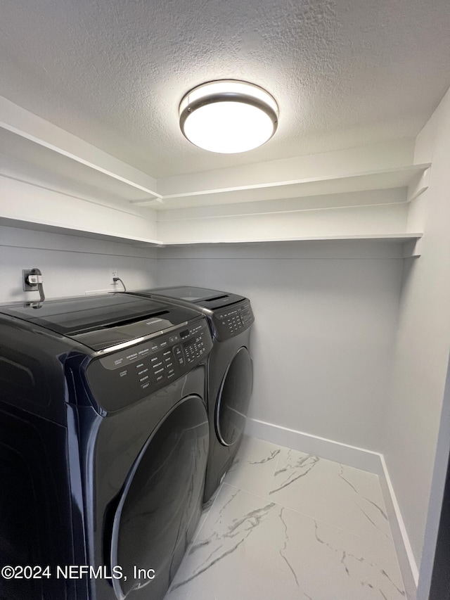 laundry area featuring a textured ceiling and washer and clothes dryer