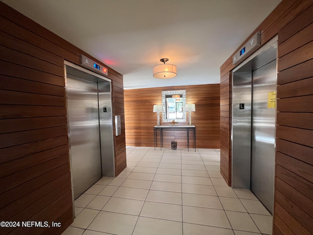 kitchen with light tile patterned flooring, wooden walls, and elevator